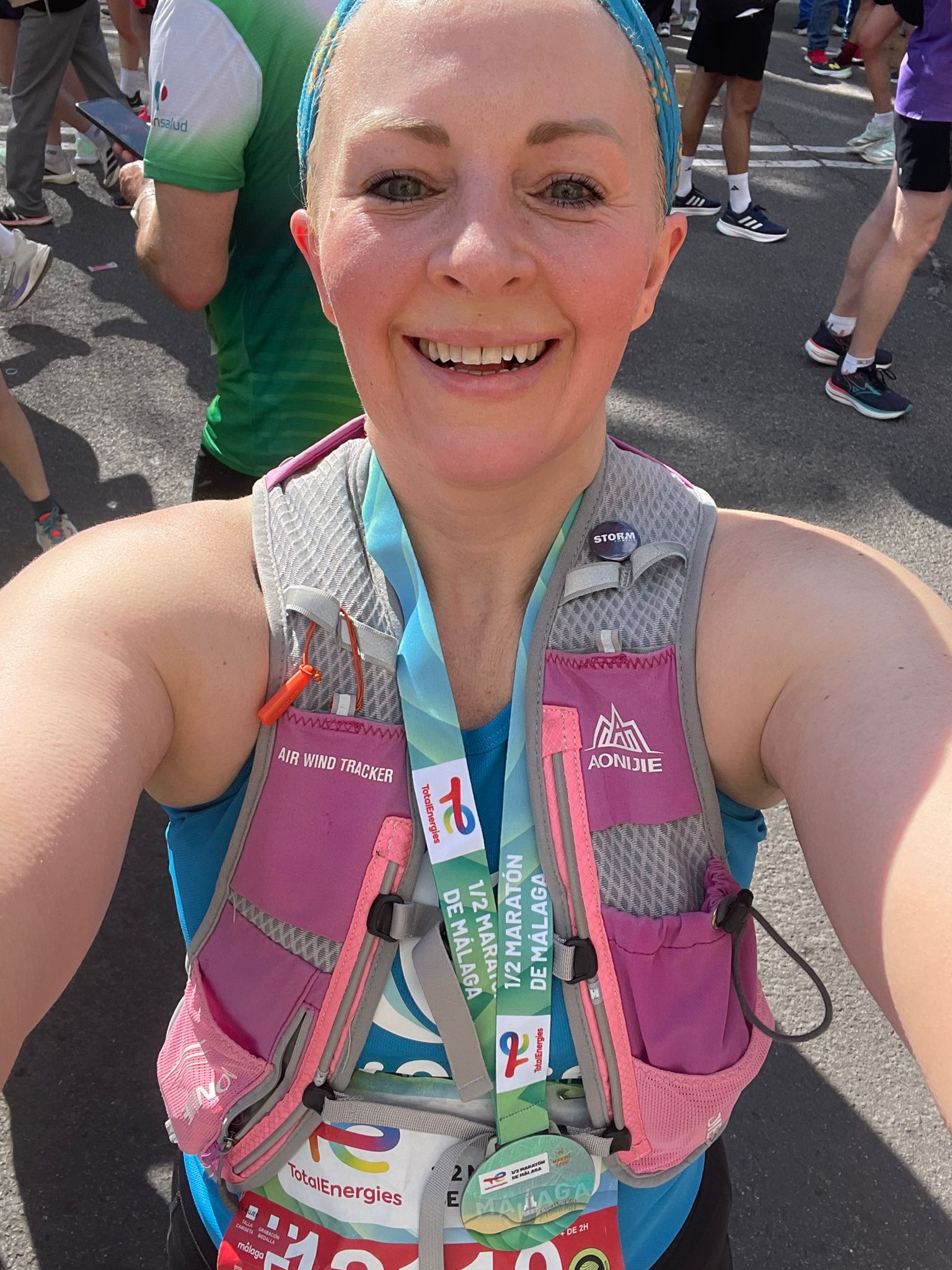 A woman takes a smilie selfie in running gear with a Malaga Half Marathon Medal on